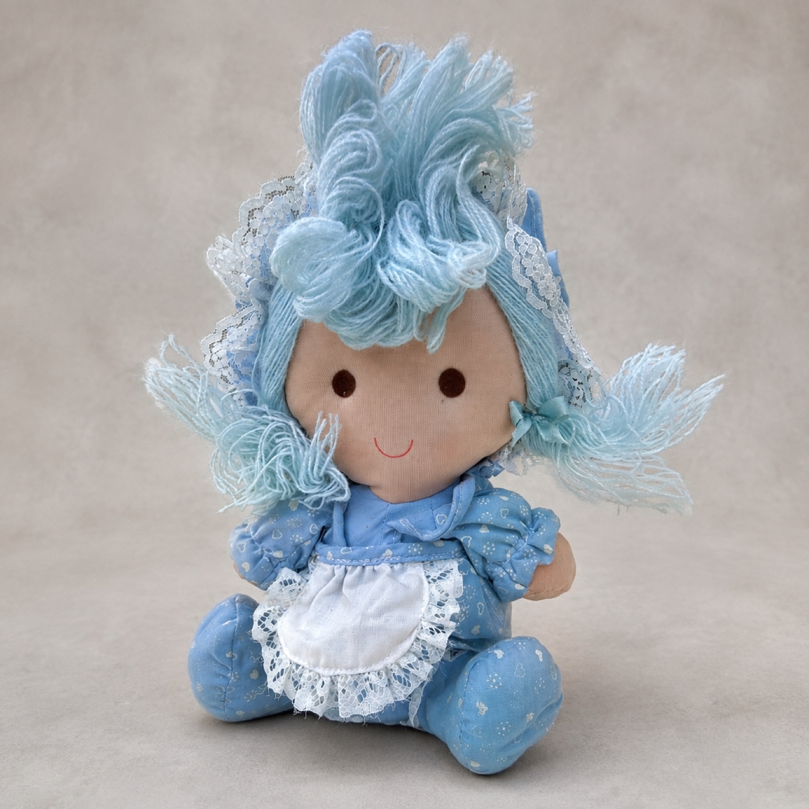 1982 Dan Dee Imports rag doll, seated front view in blue heart-and-flower print dress, white eyelet pinafore and lace bonnet