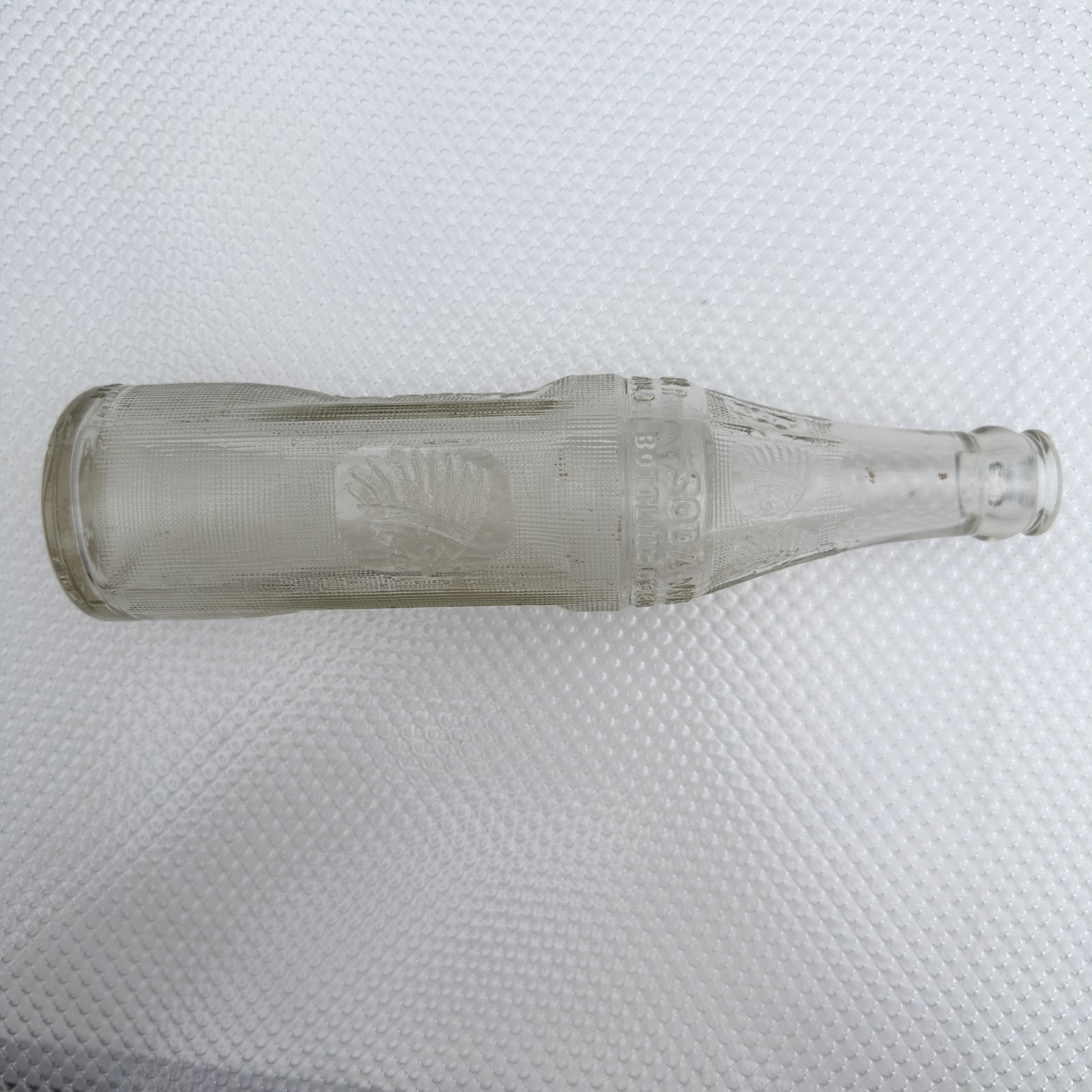 The Big Chief bottle laid on its side showing the chief head panel in raking light