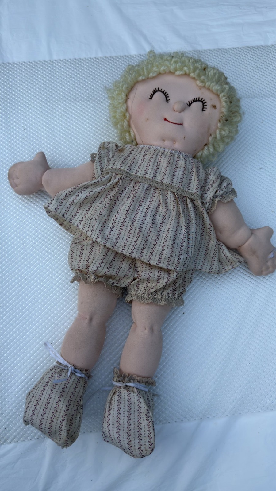 Handmade soft-sculpture baby doll, full front view — needle-sculpted sleeping face with pale yellow loop-curl yarn hair
