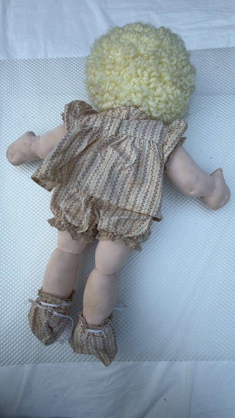 Full back view of the handmade soft-sculpture baby doll showing the yarn hair and tie-on booties