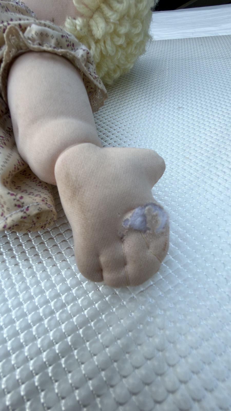 Condition detail: small worn hole on the sole of one foot of the soft-sculpture doll