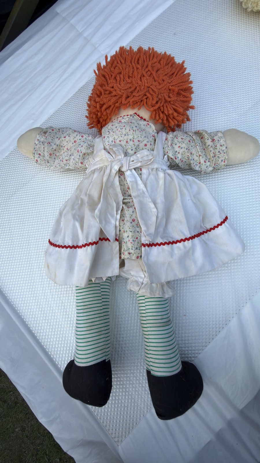 Closer back view of the Raggedy Ann doll's yarn hair, dress seams and striped legs