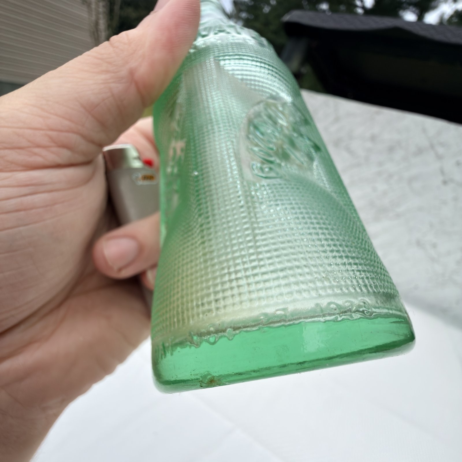 Angled view of the green bottle showing the waffle-grid texture and base