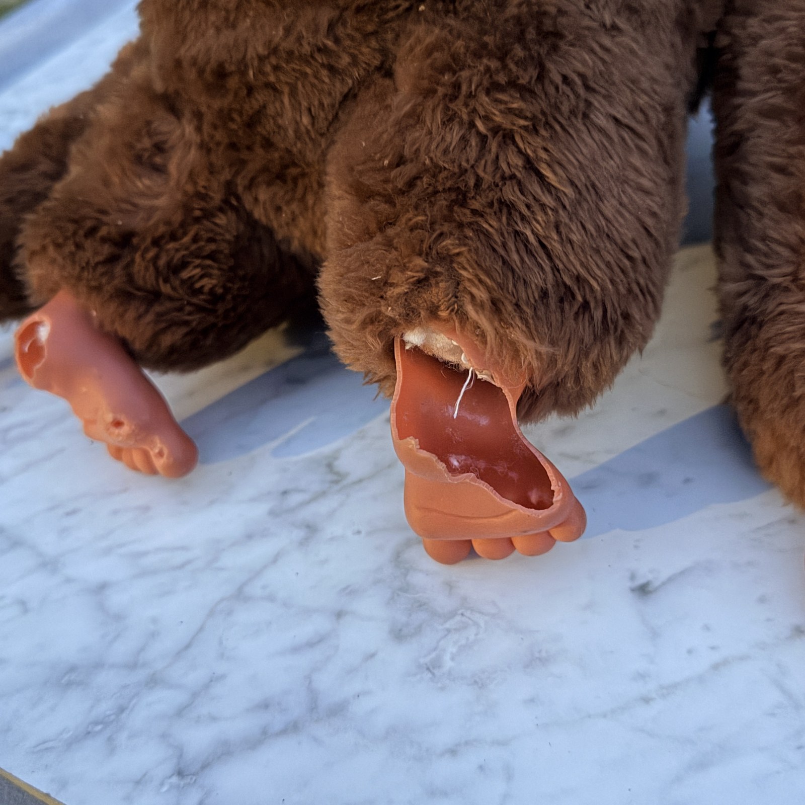 Close-up of one molded foot: vinyl broken away across the instep with the interior stuffing visible