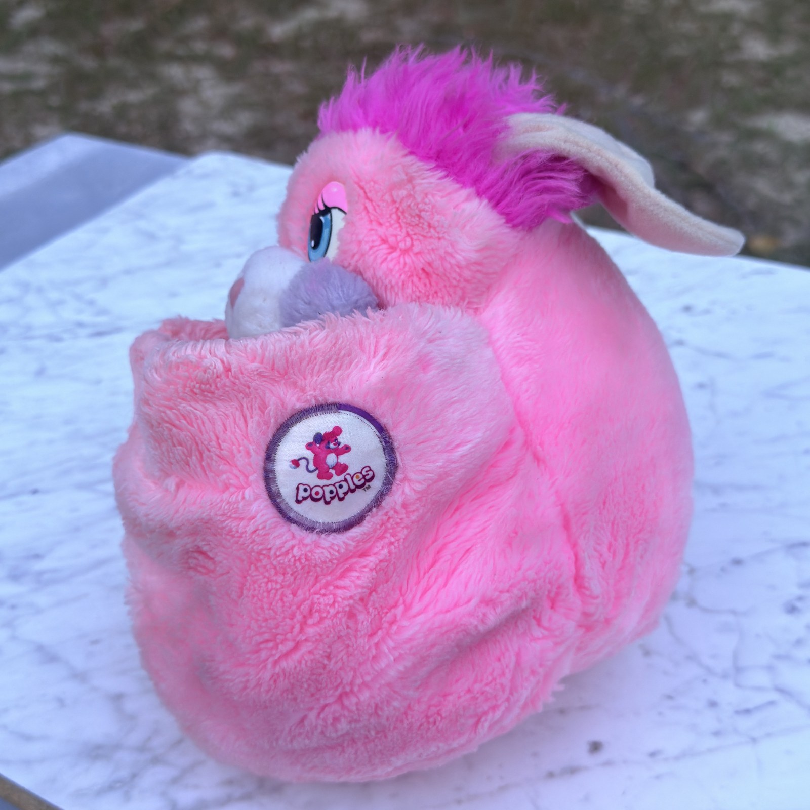 Party Popple tucked into its reversible pink pouch in the ball shape, Popples logo patch visible
