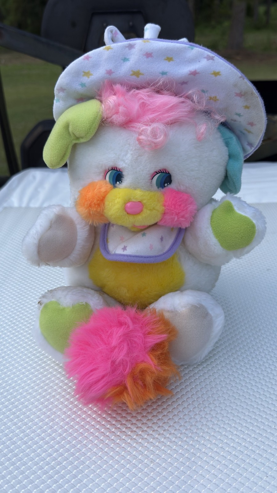 1986 Mattel Baby Cribsy Popple seated front view — white plush with curly pink hair, pastel star-print bonnet and bib