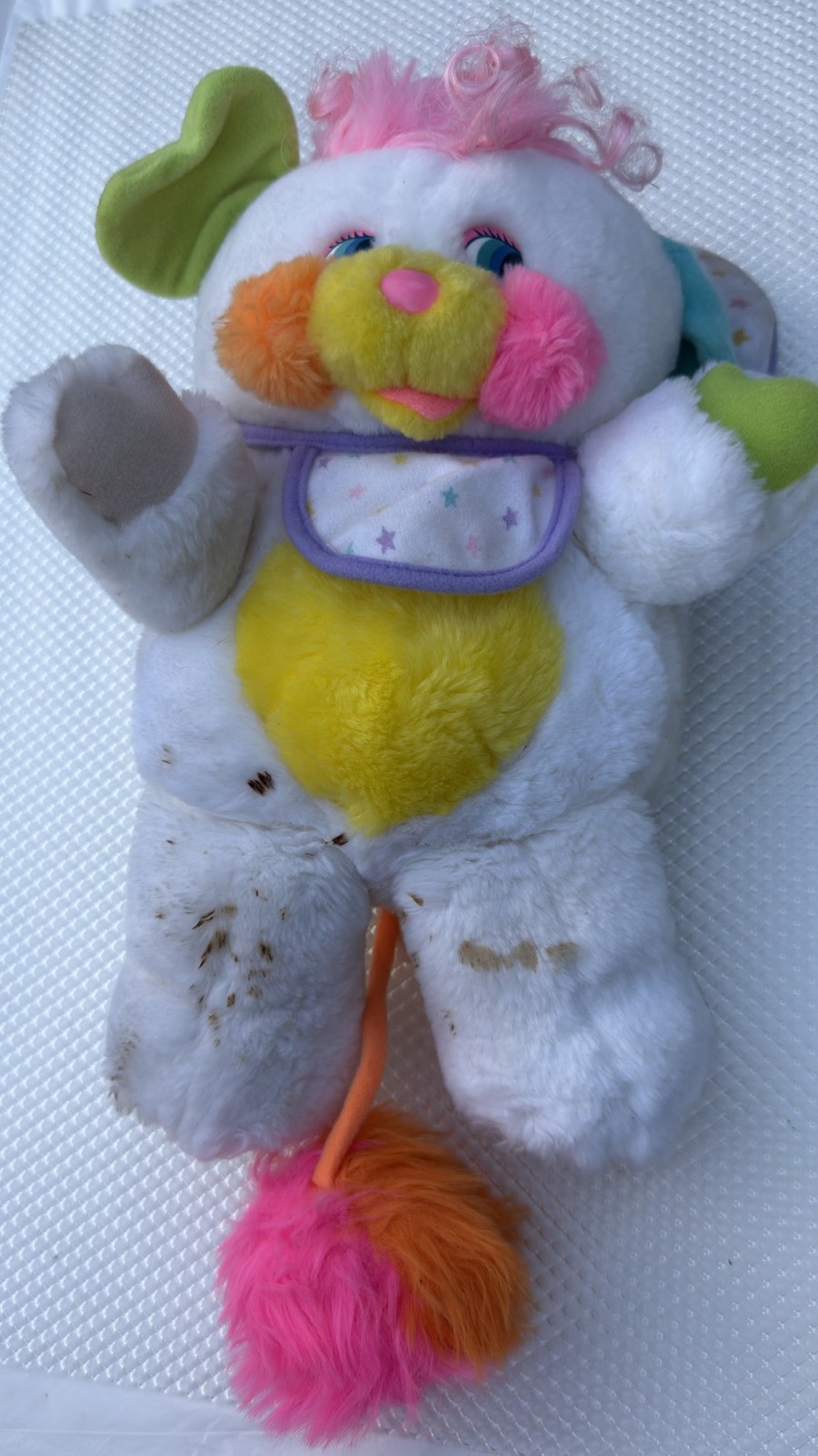 Condition detail: Baby Cribsy Popple laid flat, closer view of the soft yellow tummy with small dark spots visible