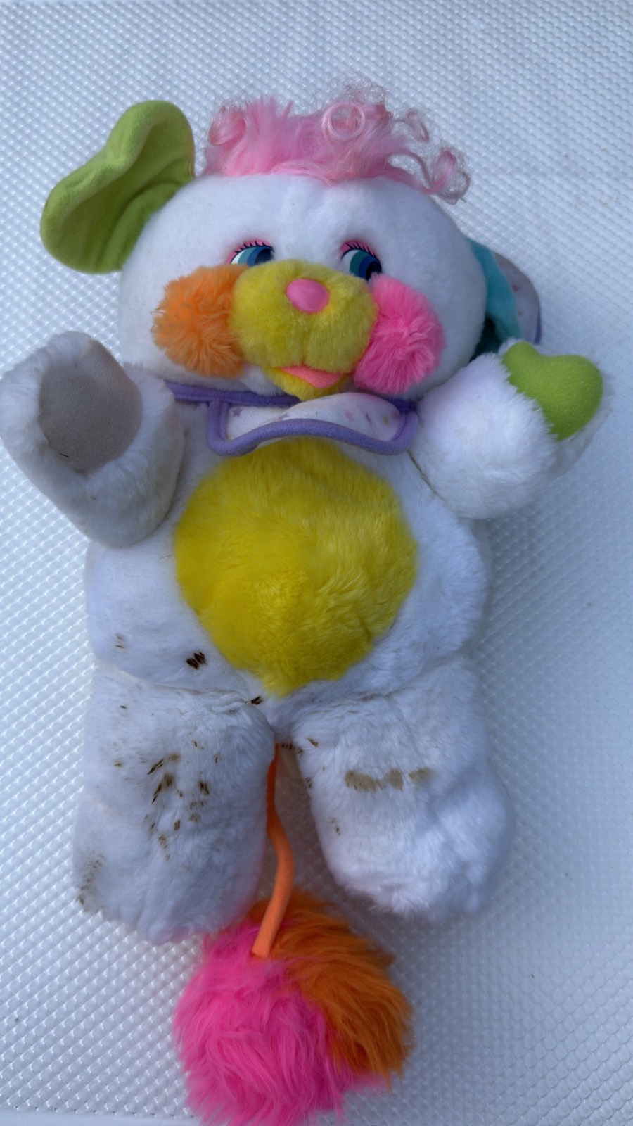 Baby Cribsy Popple laid flat, front view showing scattered soiling and light graying of the white plush