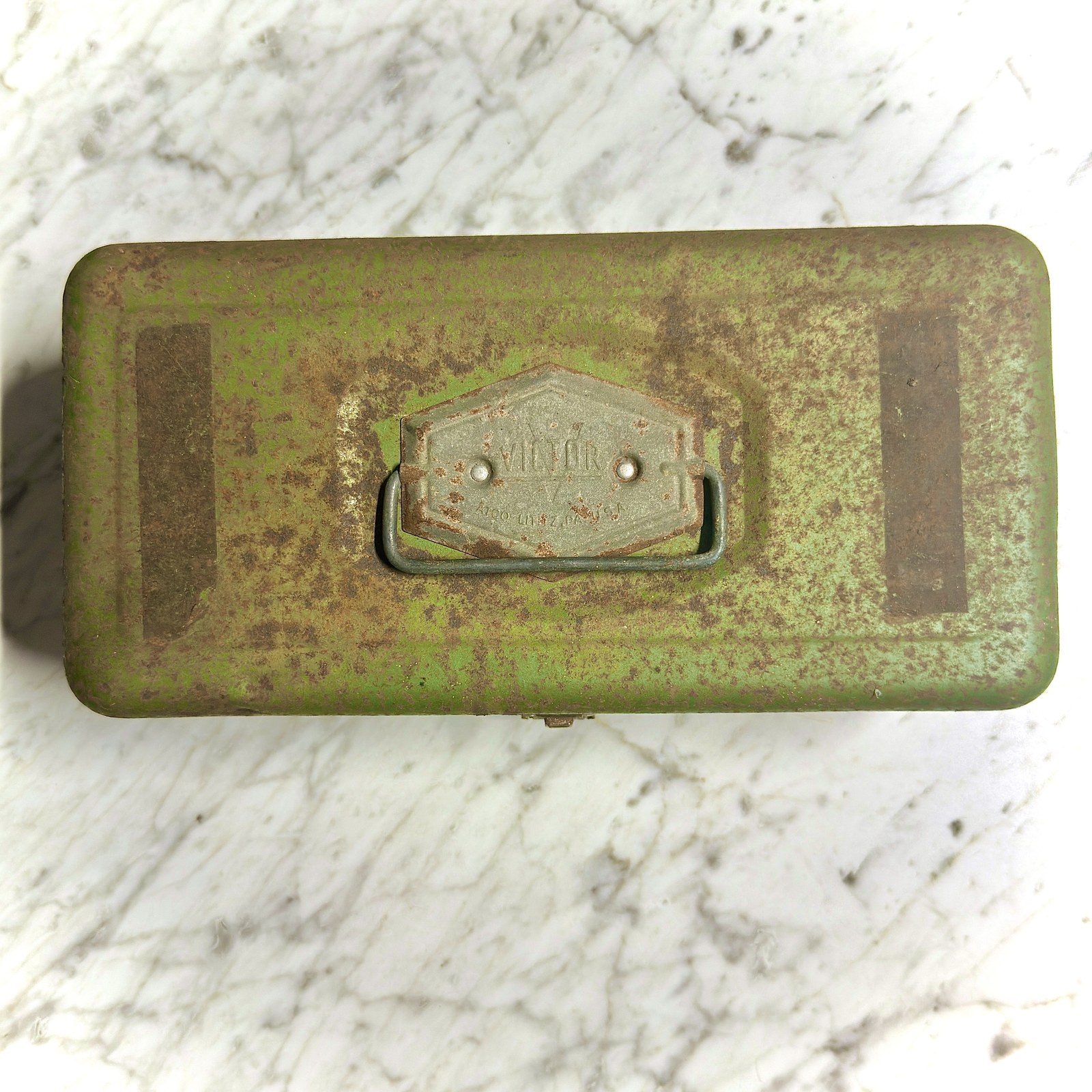 Closed top view of the case showing paint loss, rust, and the handle badge